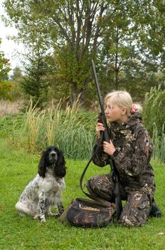 Blonde in camouflage with a gun and russian hunting spaniel.