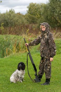 Blonde in camouflage with a gun and russian hunting spaniel.