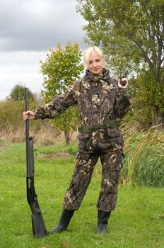 Blonde in camouflage with a shotgun and a pistol.