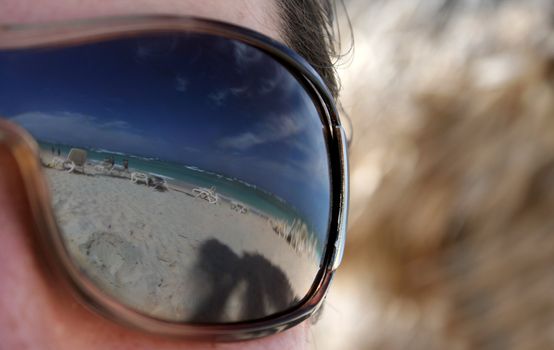 A closeup shot of a woman's sunglasses with the beautiful Punta Cana (Dominican Republic) beach in the reflection in them.