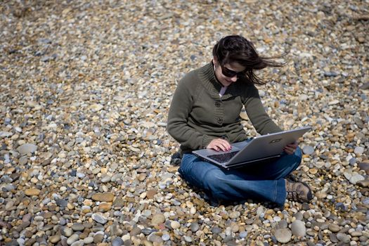 young woman with laptop computer in beach