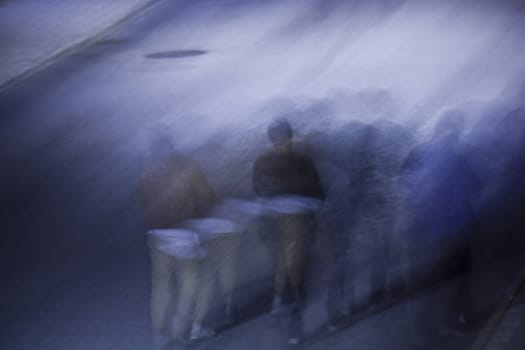 Silhouette of people walking on a sidewalk at night