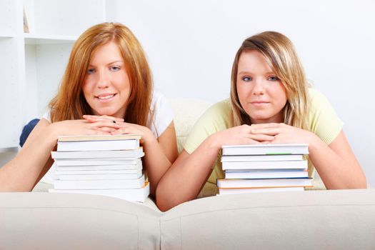Beautiful girls in home with piles of books