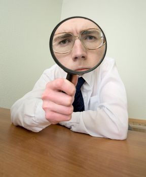 Man with a magnifier in a hand on a workplace