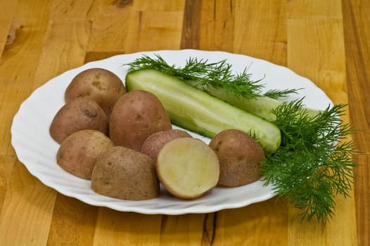 Provincial still-life with boiled potatoes, sliced salt cucumber and some dill on white porcelain  plate