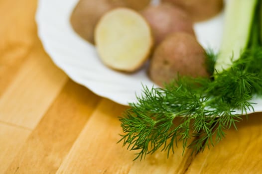 Provincial still-life with boiled potatoes, sliced salt cucumber and some dill on white porcelain  plate