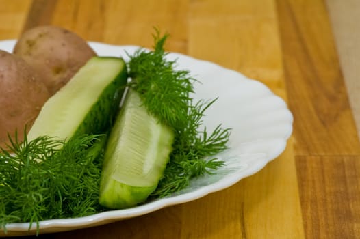 Provincial still-life with boiled potatoes, sliced salt cucumber and some dill on white porcelain  plate