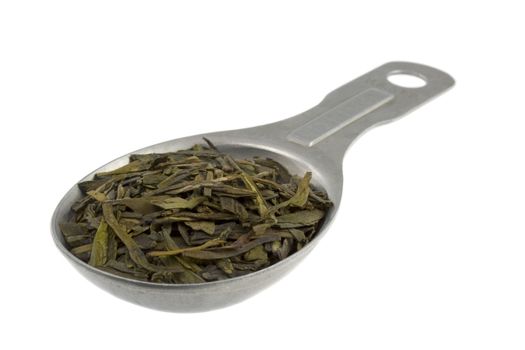 full leaf loose green tea on an old aluminum measuring tablespoon, isolated on white