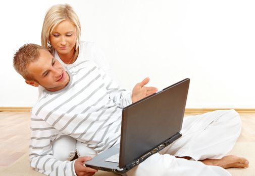 Portrait of a talking couple sitting on the floor with laptop