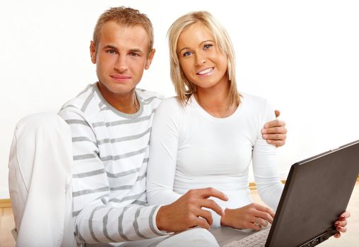 Portrait of a happy couple sitting on the floor with laptop