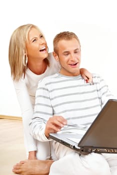 Portrait of a happy couple sitting on the floor with laptop