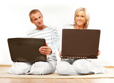 Portrait of a happy couple sitting on the floor with laptop