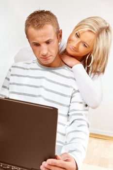 Portrait of a happy couple sitting on the floor with laptop