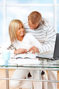 Portrait of a happy couple with laptop in home or office