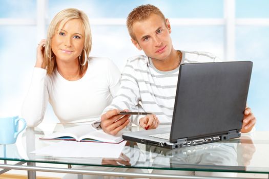 Portrait of a happy couple with laptop in home or office