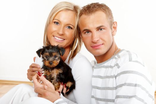 Happy couple with a funny puppy of Yorkshire Terrier