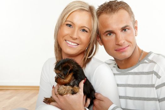 Happy couple with a funny puppy of Yorkshire Terrier