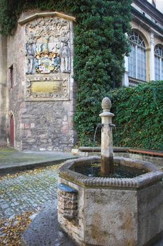 Medieval university emblem and stone fountain in Jena, Germany