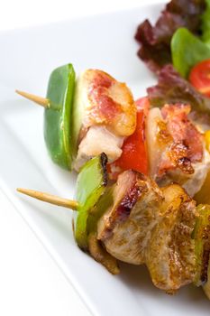 shashlik on a plate with a tomato and salad leaf