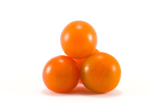 Four small cherry tomatoes piled in a pyramid on a white background