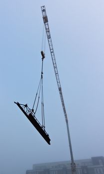 Photograph of a construction crane taken during a foggy morning