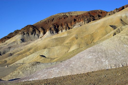 Purple, yellow, and red clay and salt mineral deposits in geological formations of Death Valley National Park