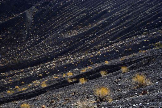 Fragment of black lava and ornage clay and salt mineral deposits in geological formations in Ubehebe Volcano, Death Valley National Park