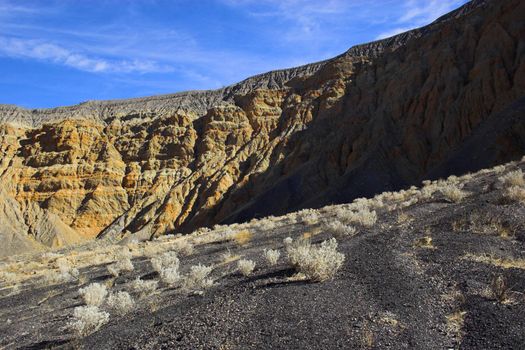 Fragment of black lava and ornage clay and salt mineral deposits in geological formations in Ubehebe Volcano, Death Valley National Park