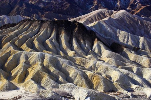 Desert landscape with multicolored yellow clay and salt mineral deposits in geological formations of Death Valley National Park