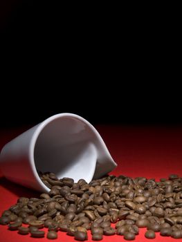 A fallen cup with coffee beans spread out.