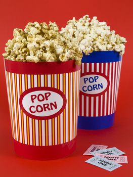 Two popcorn buckets over a red background. Movie stubs sitting aside.