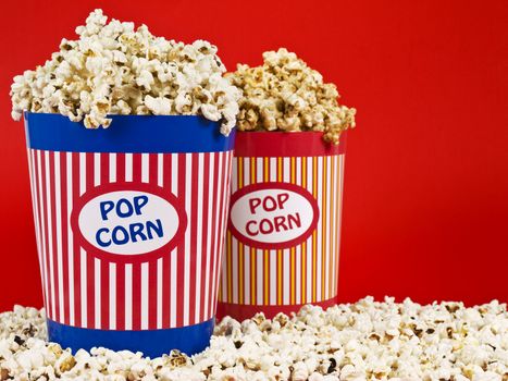 Two popcorn buckets over a red background.