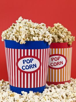 Two popcorn buckets over a red background.