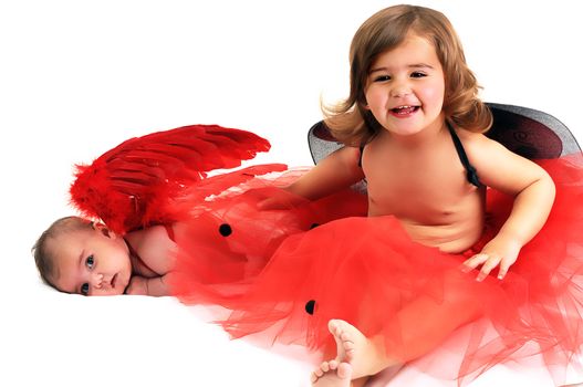 two sisters playing and smiling in studio wearing red angle wings