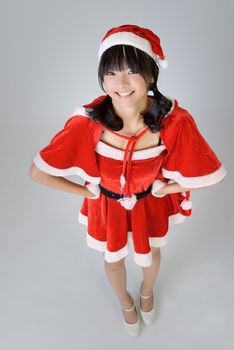Happy smiling Christmas girl looking at you against gray background.