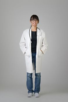 Chinese doctor of female with friendly expression over gray studio background.