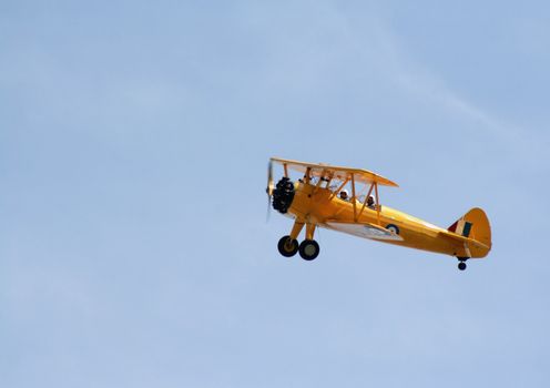 A bright yellow biplane gliding through the sky.