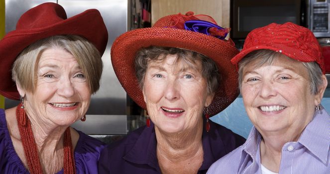 Three friendly senior women wearing red hats