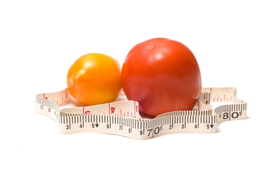 Measuring tape around a red and yellow tomatoes.