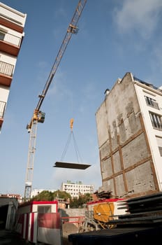 Yellow crane that carry a concrete plak above a yard