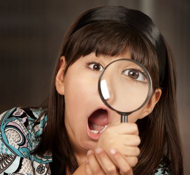 Little Hispanic girl looking through a magnifying glass