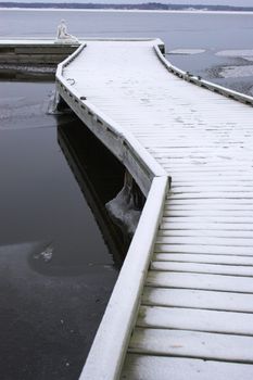 Lonely winter pier over partially frozen lake
