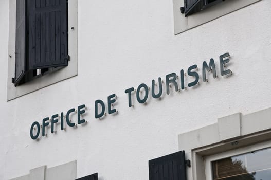 French tourism office sign on a white wall