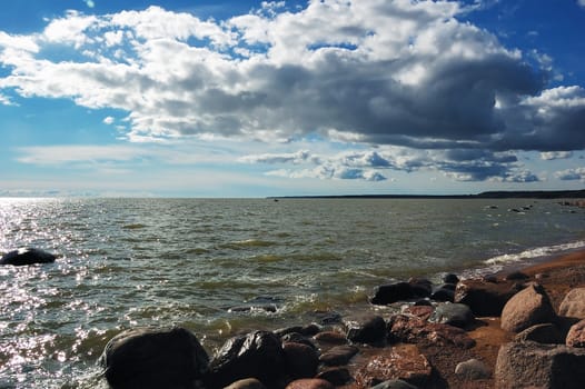 Seashore. Sun canicular day. White clouds. Dark blue sky
