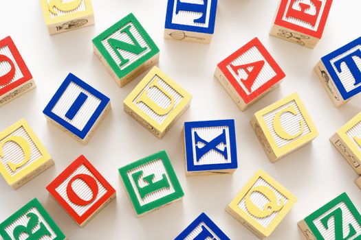 Alphabet building block scattered on white background.