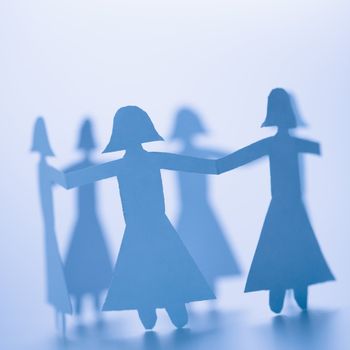 Paper cutout girls holding hands standing in circle.
