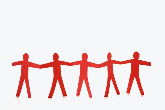 Red cutout paper men standing holding hands.