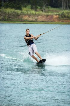 Caucasian young adult male wakeboarding on lake.