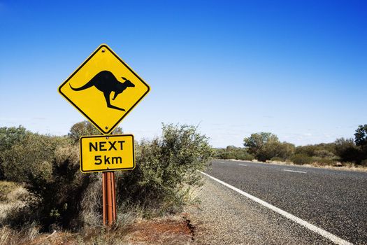 Kangaroo crossing sign by road in rural Australia.