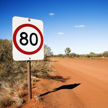 Australian kilometer per hour speed limit sign by rural dirt road.